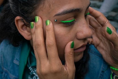 Una mujer maquilla a otra antes de comenzar la marcha.