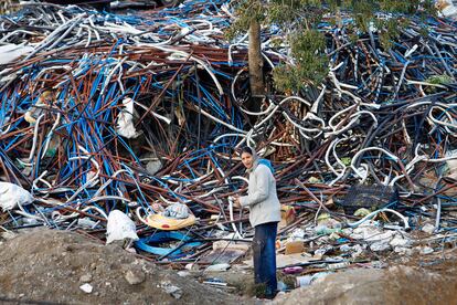 Una mujer camina entre las cubiertas que protegen el cable de cobre, y que eran separadas del metal en este poblado de chabolas de Madrid.