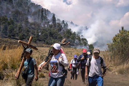 Peregrinos cruzan lo que ellos llaman "El valle del Silencio". A sus espaldas arde un incendio forestal que ha consumido todos los pastizales de uno de los cerros que forman el valle.