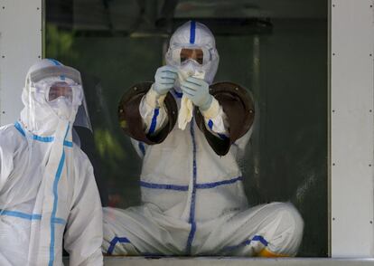 Un trabajador sanitario se pone unos guantes en una cabina de muestras antes de realizar pruebas para la detección de la Covid, en Yangón (Myanmar).