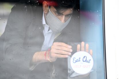 Rishi Sunak pega una pegatina en comercio en la que se exhorta a comer fuera, el pasado día 7 en la localidad escocesa de Rothesay.