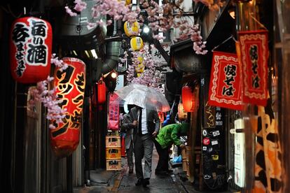 Un hombre se protege de la lluvia por una calla del distrito Shinjuku de Tokio (Japón).