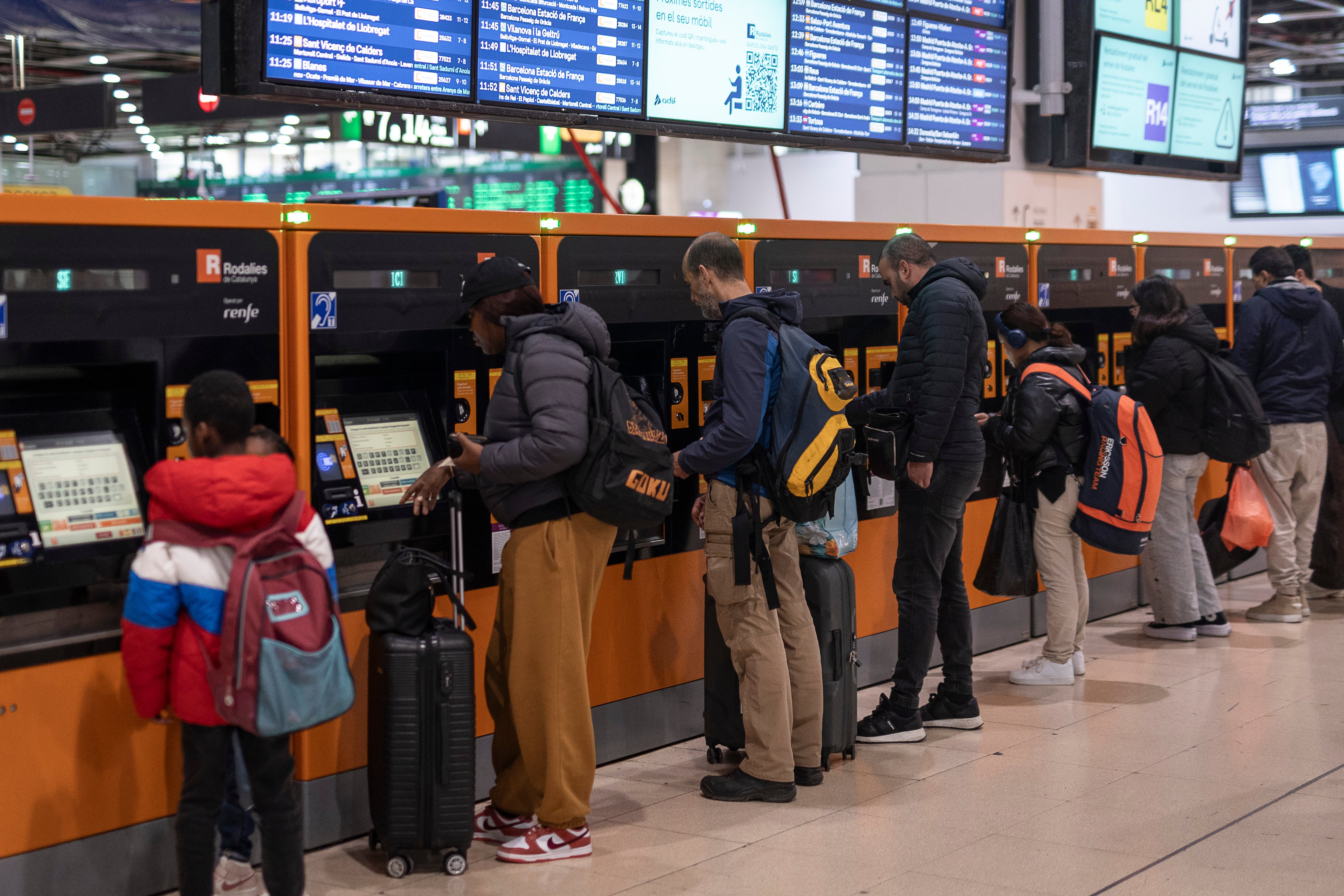 Usuarios ante las máquinas expendedoras de Sants, sacando el billete que permite viajar en Rodalies gratis durante un mes.
