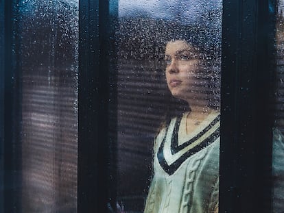 Mujer mira por la ventana durante la pandemia.
