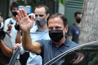 O governador paulista João Doria (PSDB) acena ao acompanhar o aliado Bruno Covas durante votação no primeiro turno da eleição em São Paulo, no domingo