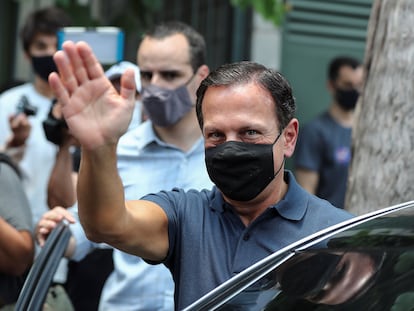 O governador paulista João Doria (PSDB) acena ao acompanhar o aliado Bruno Covas durante votação no primeiro turno da eleição em São Paulo, no domingo