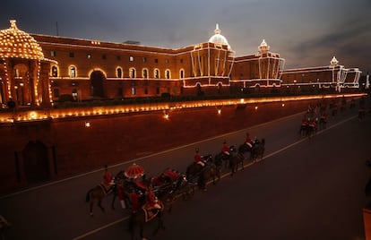 Soldados a caballo regresan después de un ensayo del desfile del día de la República en Nueva Delhi, al fondo el palacio presidencial aparece iluminado, (India).