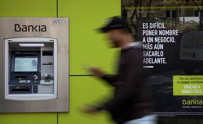 Una persona camina ante un cajero automático.