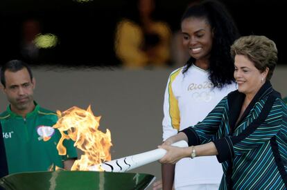 Dilma Rousseff, presidenta de Brasil enciende una antorcha con la llama olímpica junto a Fabiana Claudino, capitán del equipo brasileño de voleibol en el Palacio de Planalto en Brasilia, Brasil.