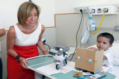 Carme Chacón observa cómo juega uno de los niños pacientes del hospital Sant Joan de Déu.