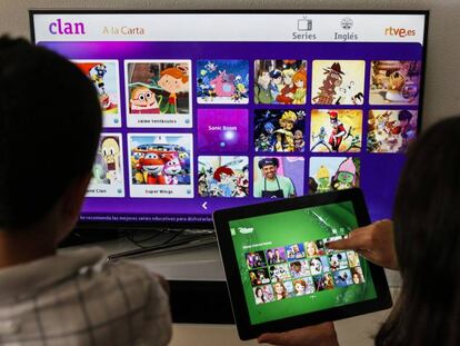 Dos niños eligen programas en una Smart TV y una tableta.