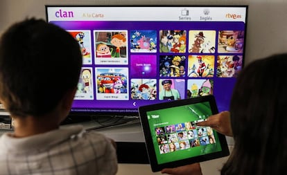 Dos niños eligen programas en una Smart TV y una tableta.