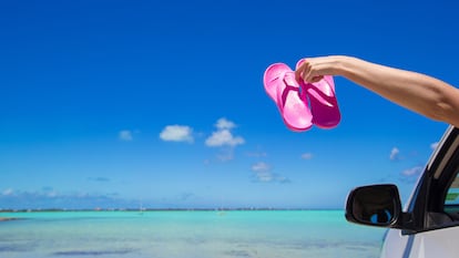 Unas chanclas rosas fuera de un coche con vistas al mar.