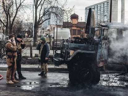 Varios soldados ucranios, el sábado junto a un vehículo militar de su ejército calcinado en Kiev.