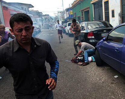 Um homem atende jovem baleado na segunda-feira durante um protesto em San Cristóbal, na Venezuela.