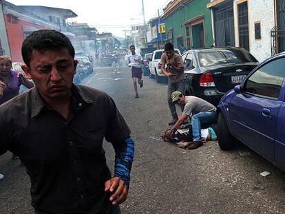 Um homem atende jovem baleado na segunda-feira durante um protesto em San Cristóbal, na Venezuela.