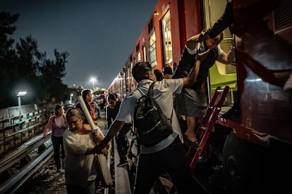 Un usuario ayuda a descender a mujeres mayores de uno de los vagones en el tramo elevado de la línea 9 del metro. 