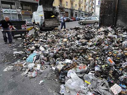 Dos trabajadores recogen basura ayer en una calle de Nápoles.
