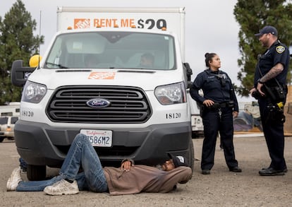 Un hombre en condición de calle protesta frente al camión de mudanza de un desarrollador immobiliario, en Oakland (California).