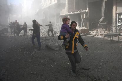 Un hombre lleva en brazos a un niño herido tras un bombardeo en Hamouria (Siria), el 19 de febrero de 2018. 