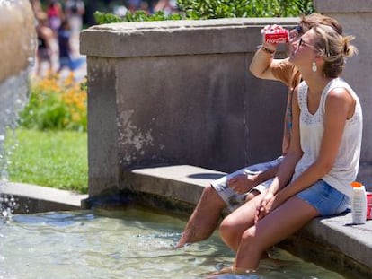 Dos j&oacute;venes se refrescan en la plaza de Catalunya de Barcelona.