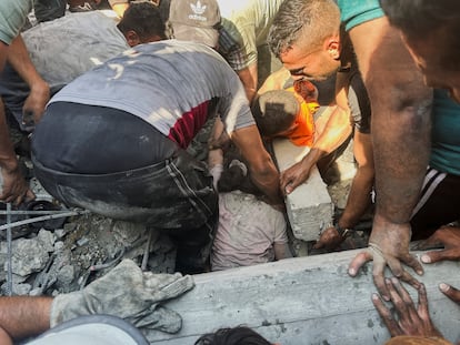 Un grupo de voluntarios rescatan a un niña de entre los escombros de un edificio tras un ataque israelí en Jan Yunis. 