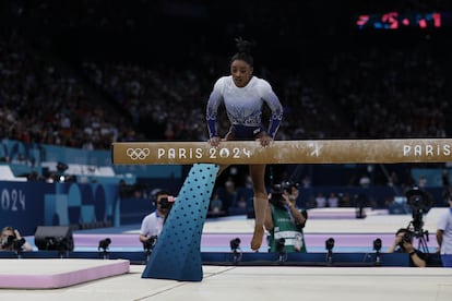 La gimnasta Simone Biles sube a la barra de equilibrio tras su caída durante su ejercicio.