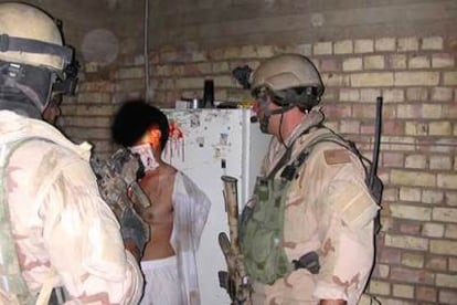 Dos presuntos <i>marines</i> custodian a un hombre con una herida en la cabeza.