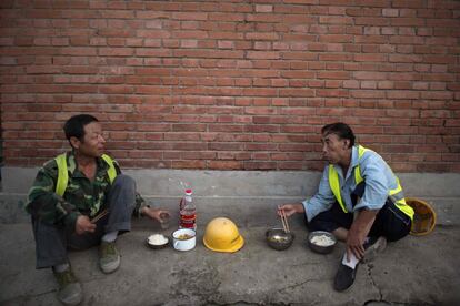 En China hay cientos de millones de ‘migrantes’ internos, campesinos que se establecen en la capital en busca de trabajos mejor pagados. En la foto, trabajadores de la construcción comen en una calle tras su jornada.