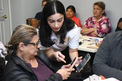 Claudis Rivera, reportera de asuntos políticos y de inmigración de Enlace Latino, ayuda a una mujer a inscribirse a la comunidad de WhatsApp durante una charla en Mount Olive, en 2024.