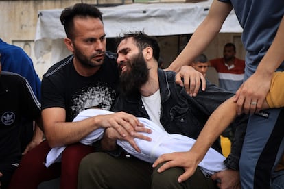 A man holds the body of his son, who died in an airstrike, before his burial in Khan Younis, south of the Gaza Strip.