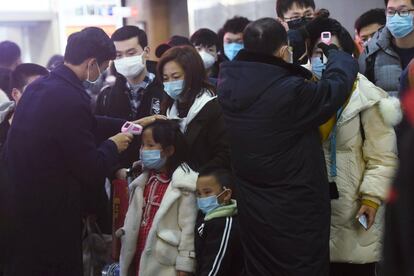 Los miembros del personal verifican la temperatura corporal de los pasajeros que llegan del tren de Wuhan a Hangzhou, en la estación de trenes de Hangzhou, antes del Año Nuevo Lunar chino en la provincia de Zhejiang, el 23 de enero.