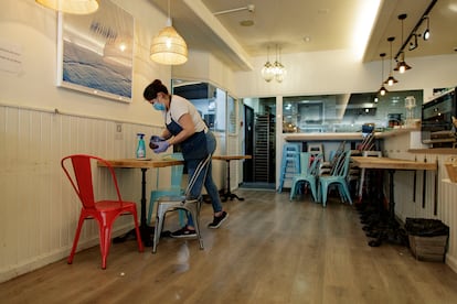 Una camarera limpia una mesa de la Panadería Madrid Delicia.