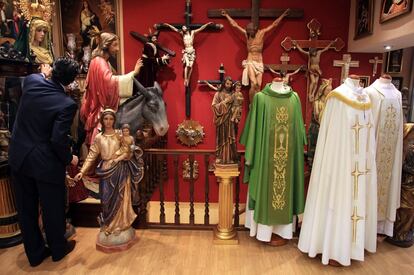 Jesús coloca uno de los pasos de Semana Santa y cuida que no falte ningún detalle en su tienda de artículos religiosos El Ángel, en la calle de Esparteros, en Madrid.