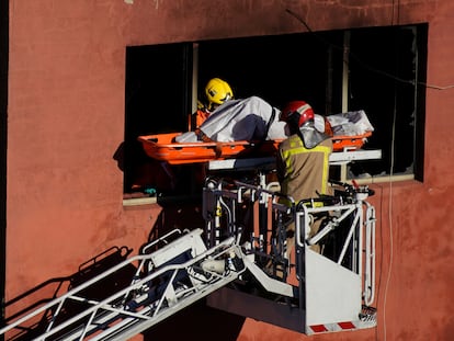 Los bomberos trasladan el cuerpo de una de las víctimas del incendio.