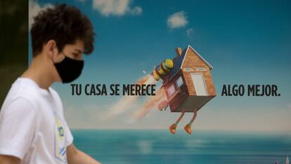 Un joven con mascarilla para ante el anuncio de un producto hipotecario, el pasado julio en Madrid.