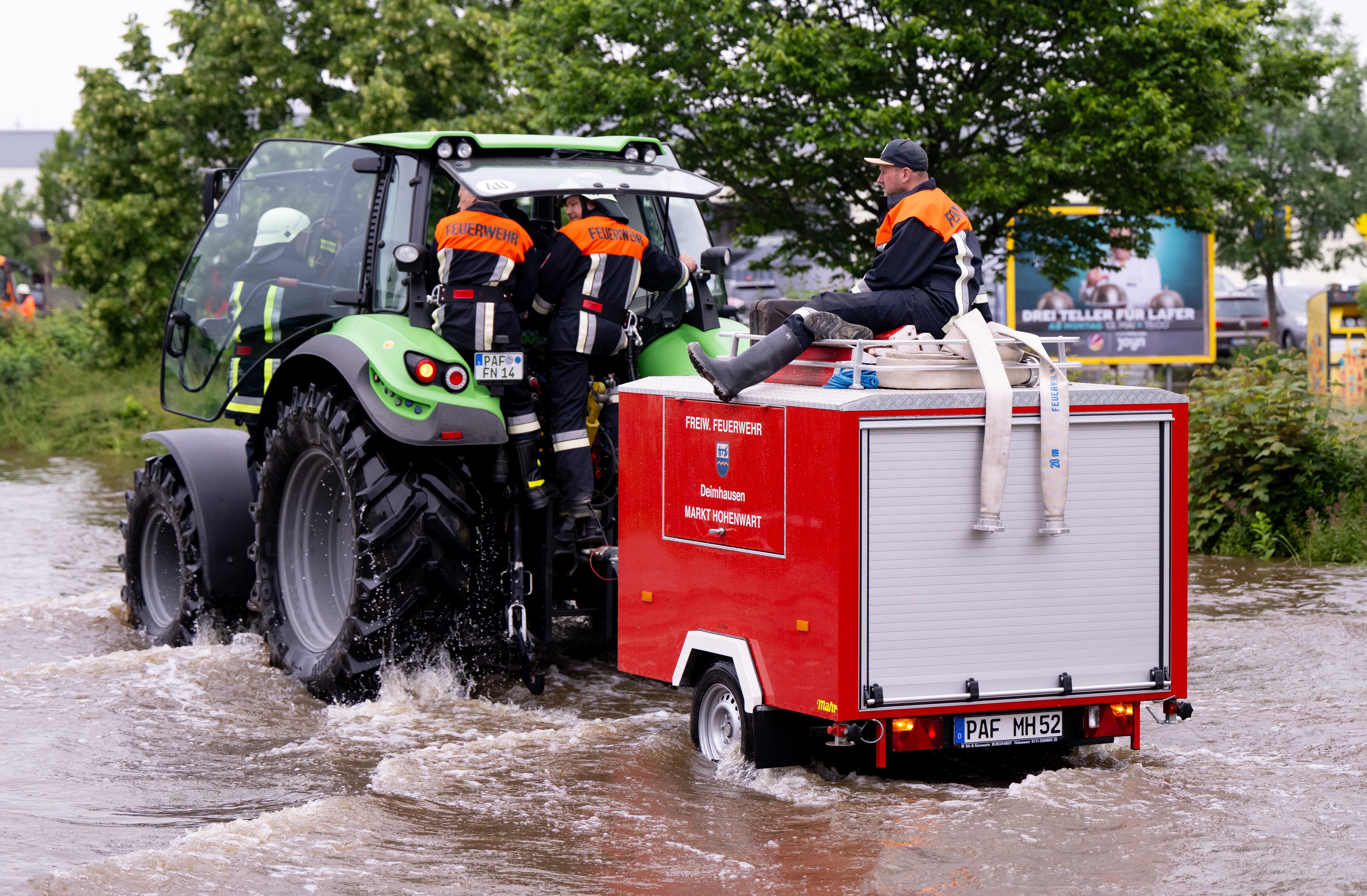 Un equipo de bomberos conducen un tractor en una carretera inundada, este domingo en Reichertshofen, Baviera.