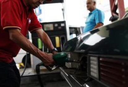 Un hombre sirve combustible en una estaci&oacute;n de servicio de gasolina.