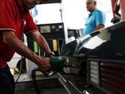 Un hombre sirve combustible en una estaci&oacute;n de servicio de gasolina.