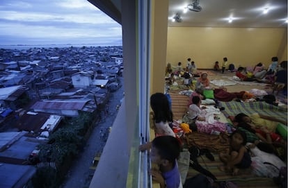 Dos niños miran por una ventana del centro de evaciuación que les corresponde, cerca de Manila. Poco a poco los miles de refugiados que ha causado el tífón comienzan a regresar a sus hogares.