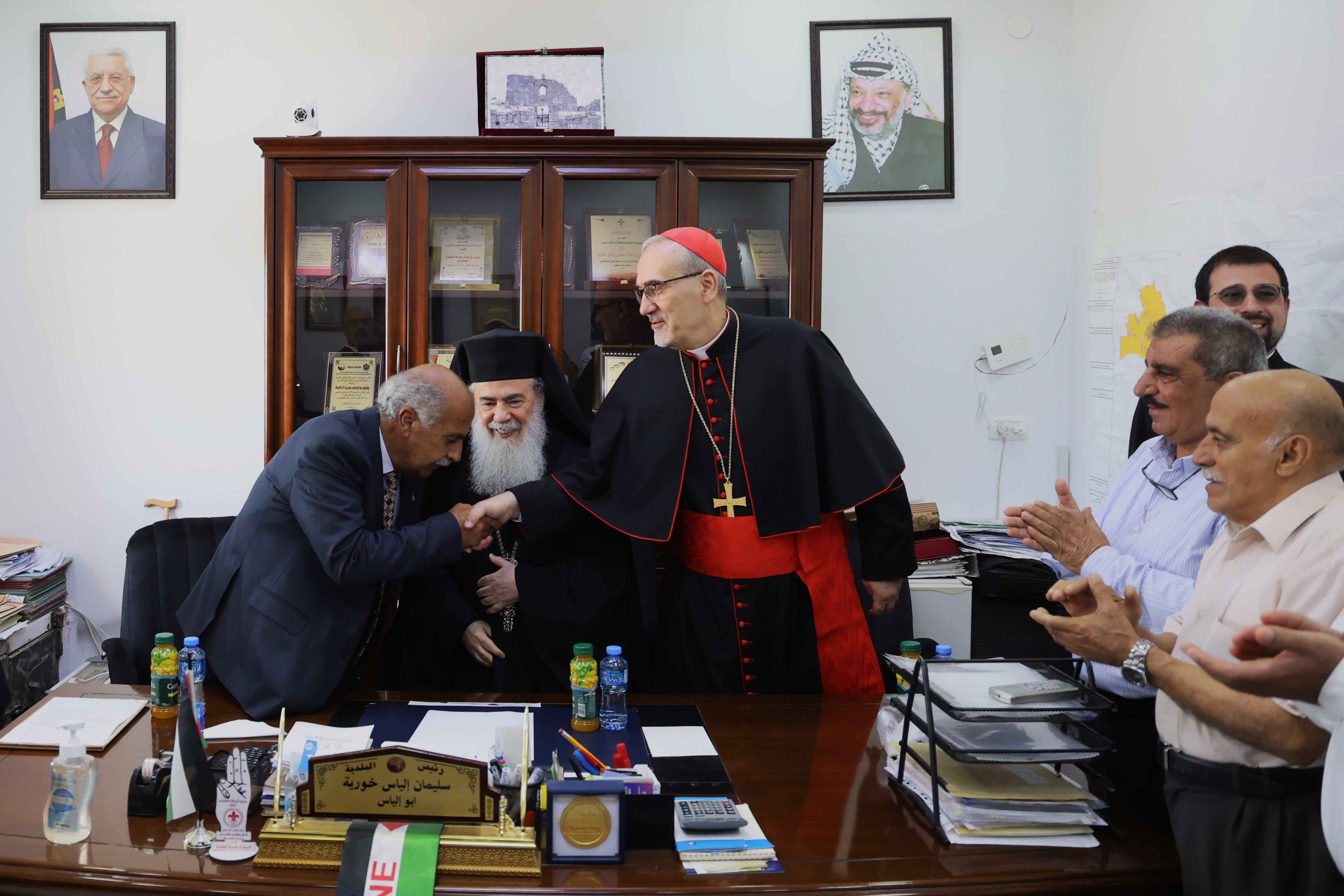 El patriarca Teófilo III, de la iglesia ortodoxa griega (en el centro) y el
Cardenal Pierbattista Pizzaballa (jefe de los católicos en Tierra Santa), saludan este lunes al alcalde de Taybeh.