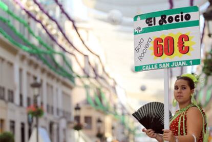 Una mujer anuncia ofertas de prendas para la Feria de Málaga.