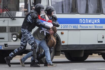 Fuerzas especiales de la policía detienen a un manifestante cubierto por una bandera rusa en Moscú.