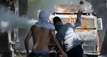 Manifestantes se enfrentan con la policía ayer, jueves, durante los disturbios tras la marcha convocada por los estudiantes en Santiago.
