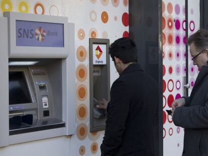Dos personas sacan dinero de un cajero de SNS.