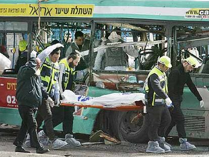 Personal sanitario traslada un cadáver delante del autobús en el que se inmoló el suicida palestino.
