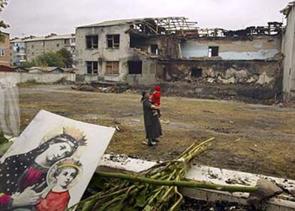Una mujer vuelve con un niño al patio de la destrozada escuela Número Uno de Beslán.
