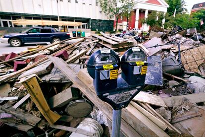 Flooding debris is stacked along State Street, near the state capital building, as a vehicle drives past with a load of lumber tied to the roof in downtown, Tuesday, Aug. 1, 2023, in Montpelier, Vt