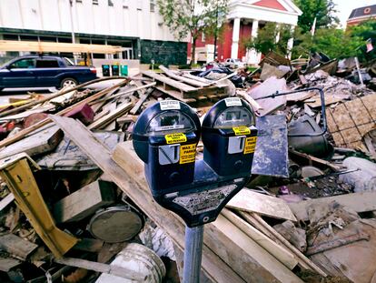 Flooding debris is stacked along State Street, near the state capital building, as a vehicle drives past with a load of lumber tied to the roof in downtown, Tuesday, Aug. 1, 2023, in Montpelier, Vt.