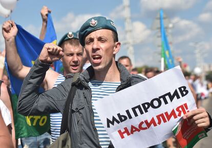 Un militar del ejercito aéreo grita mientras porta un cartel que dice "¡Estamos contra la violencia!", durante un mitin de la oposición en el centro de Minsk.